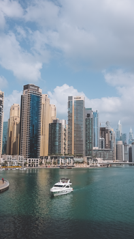 Scenic view of Dubai Marina with skyscrapers and a yacht on a sunny day.