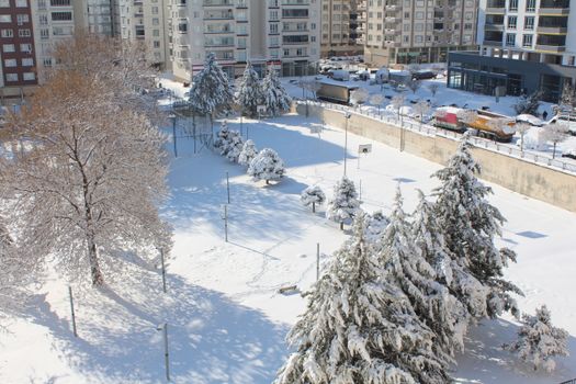 A serene winter scene of a snow-covered urban park in Gaziantep.