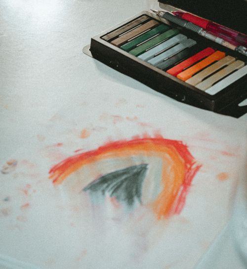 Free Artistic pastel crayons with a rainbow drawing on paper, showcasing creativity and color blending. Stock Photo