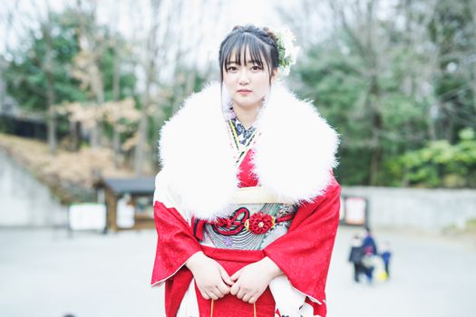 Elegant portrait of a woman in a vibrant traditional kimono outdoors.