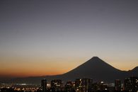 A beautiful cityscape at dawn with a mountain silhouette and urban skyline under a vibrant sky.
