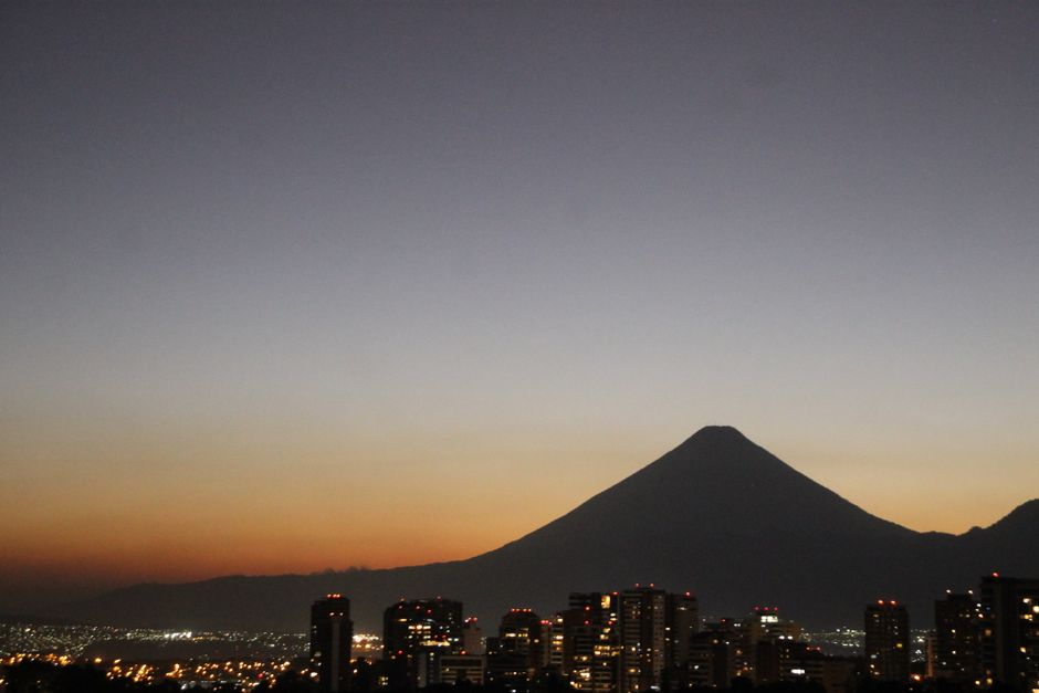 A beautiful cityscape at dawn with a mountain silhouette and urban skyline under a vibrant sky.