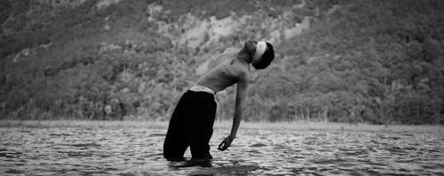 A Grayscale of a Blindfolded Man in a Lake