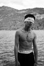 Man Standing with Eyes Covered with Band with Hills and Lake in Background