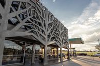 Contemporary architecture of a gas station with a tree-inspired concrete facade.
