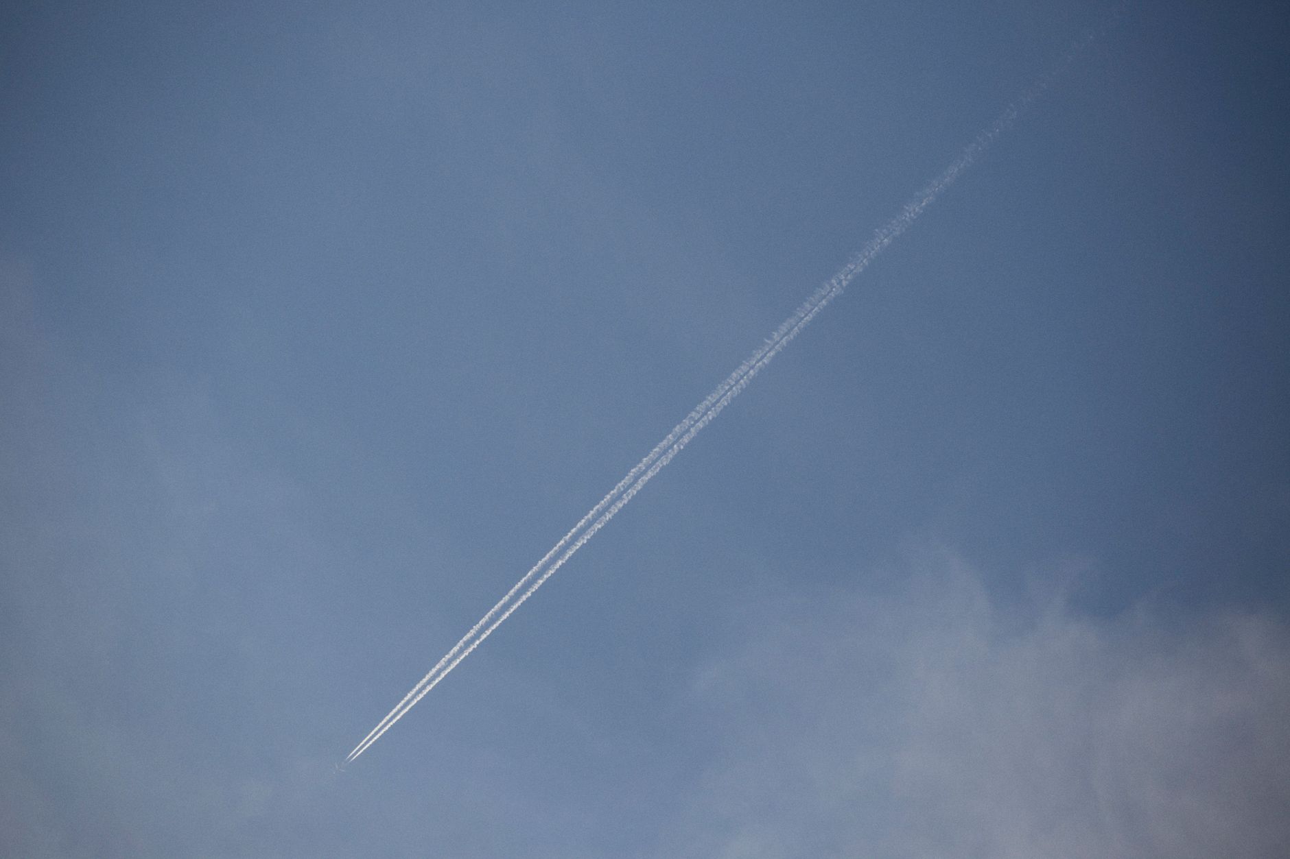 A long airplane vapor trail slicing through a clear blue sky, showcasing travel and aviation themes.