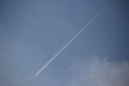 A long airplane vapor trail slicing through a clear blue sky, showcasing travel and aviation themes.