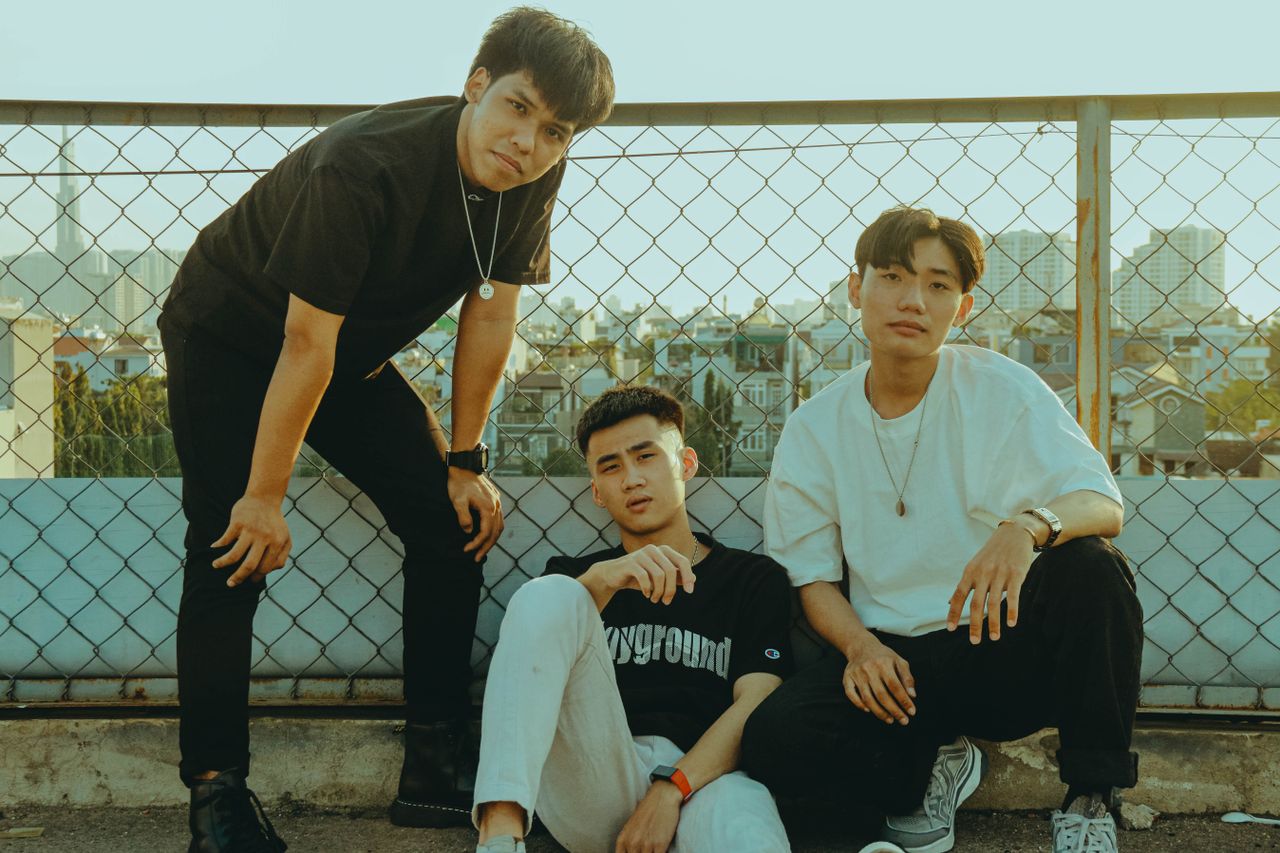three friends hanging out on a rooftop with a city view behind them