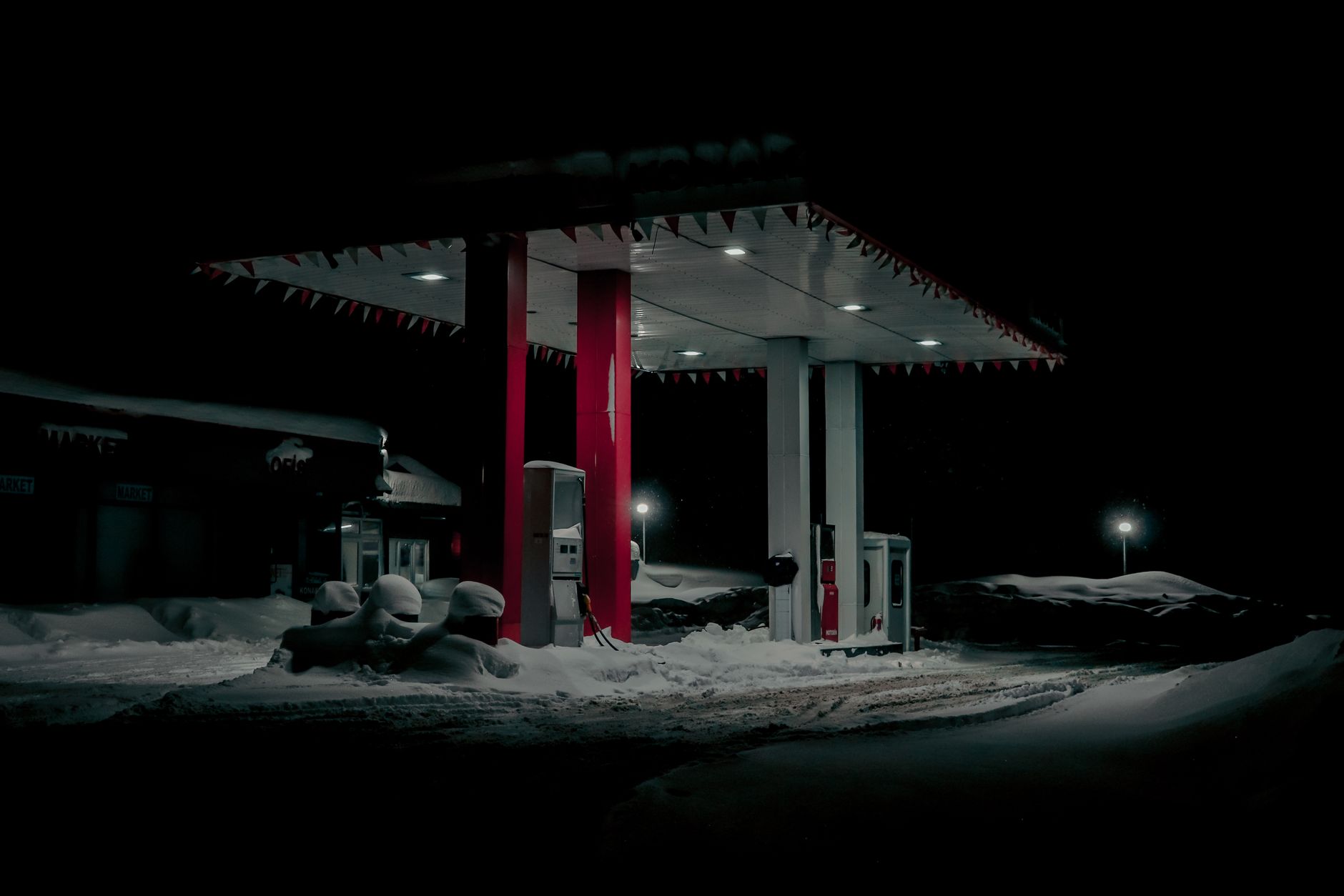 A gas station surrounded by heavy snow under nighttime illumination.