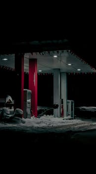 Illuminated gas station covered in heavy snow during a cold winter night.