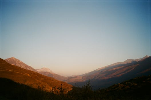 Peaceful view of mountain ranges during sunset with a clear sky.