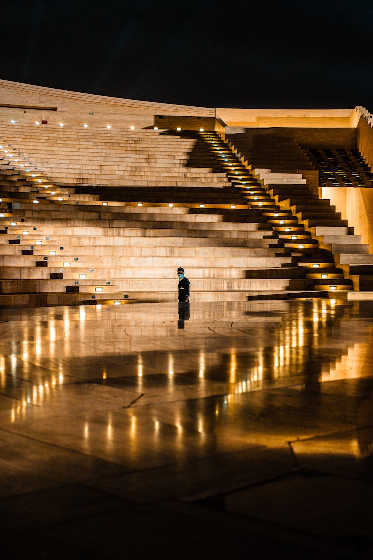 A Person Standing In An Amphitheater At Night