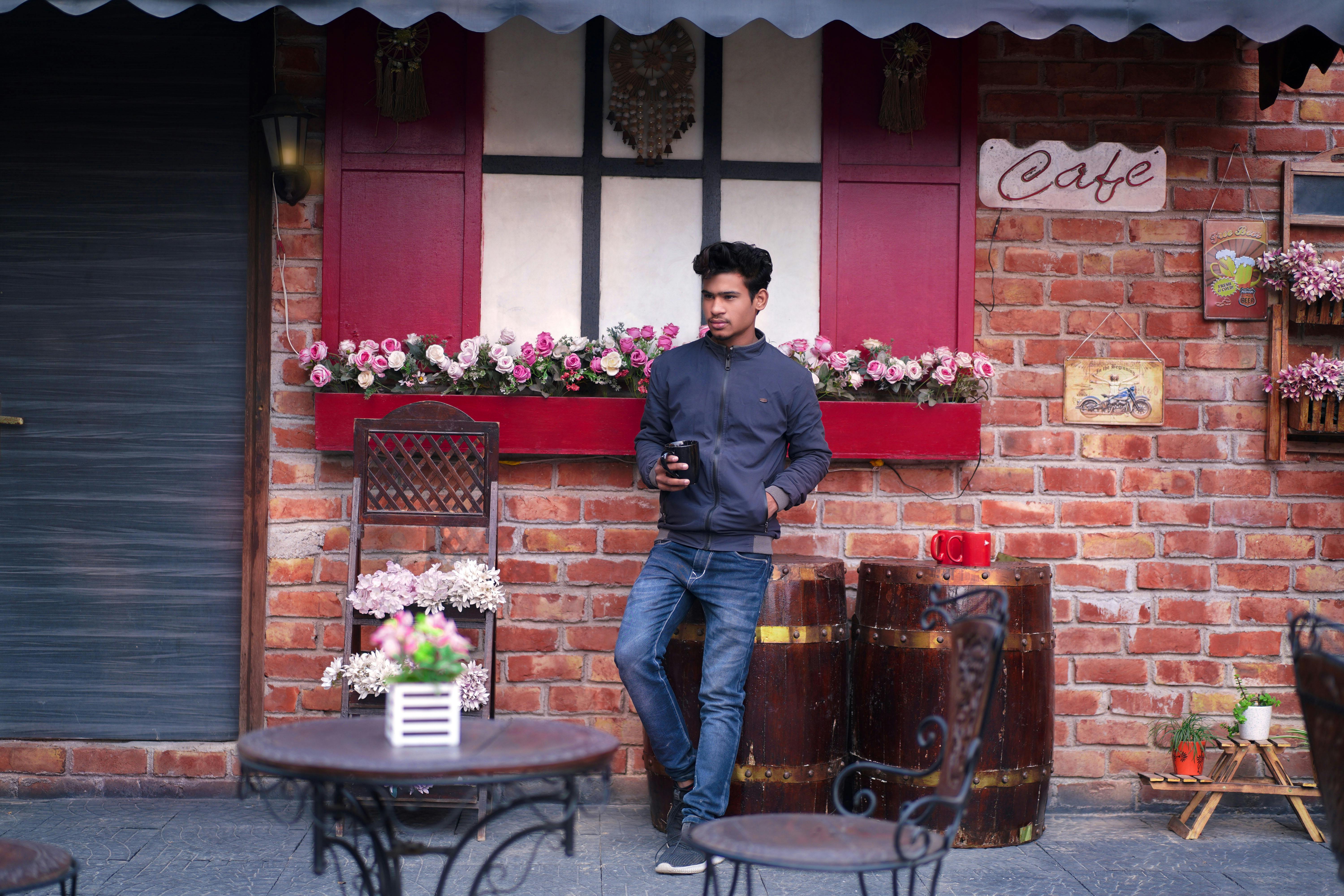 Young man with coffee at a rustic outdoor cafe