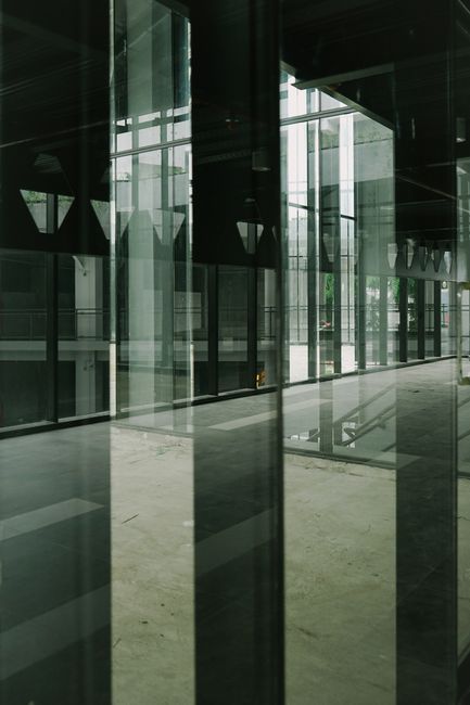 Interior view of a modern building with reflective glass surfaces creating abstract reflections.