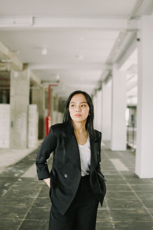 Free Elegant woman in business attire standing confidently in a contemporary corridor setting. Stock Photo