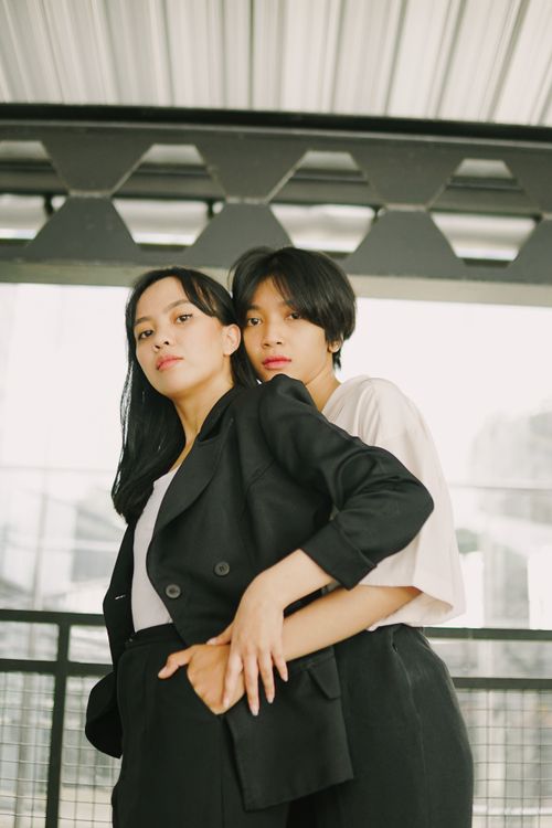 Free Portrait of two stylish young women embracing indoors. Fashionable and intimate setting. Stock Photo