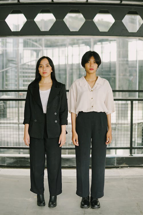 Two Young Women Wearing Office Outfits Standing Side by Side