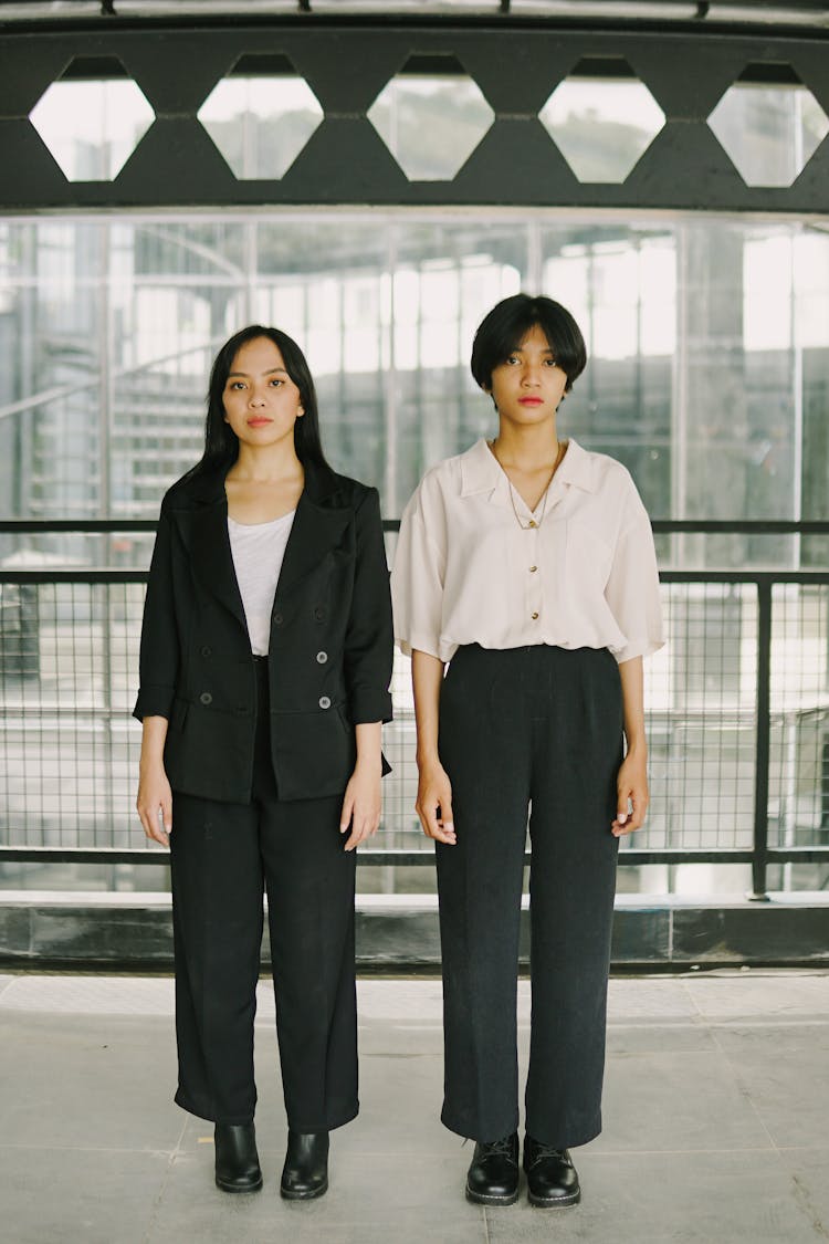 Two Young Women Wearing Office Outfits Standing Side By Side