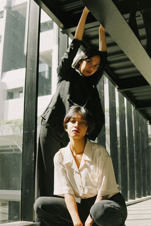 Free Modern portrait of two young women posing stylishly in a sunlit indoor setting. Stock Photo