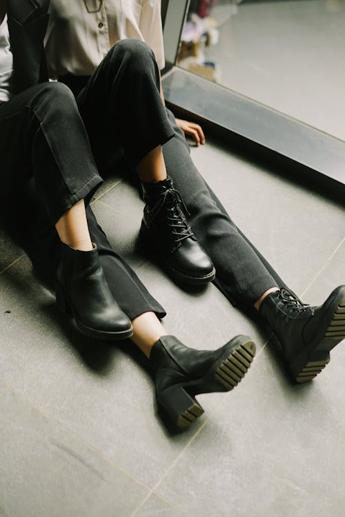 Legs of Two Unrecognizable People in Black Pants and Shoes Sitting on Floor