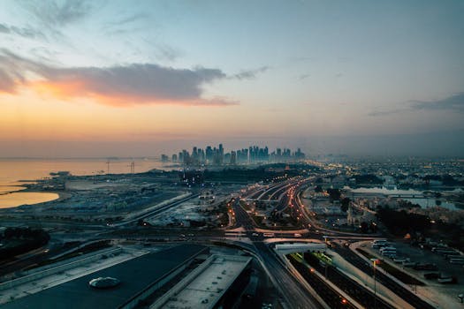 A stunning aerial view of a cityscape at dusk with illuminated highways and beautiful sunset.