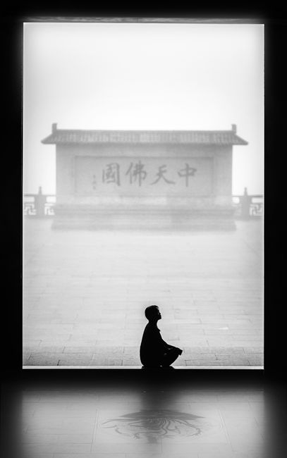 Silhouette of a person meditating in front of a misty, ancient Chinese temple.