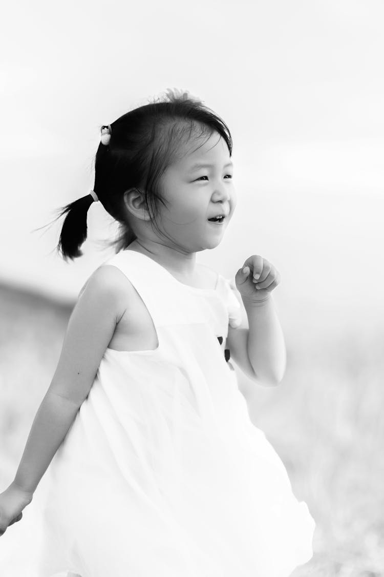 Little Girl With Ponytails Wearing White Dress Smiling And Dancing