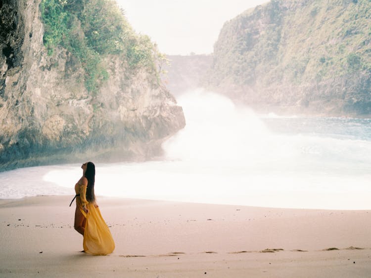 Woman In Yellow Dress Walking On Beach 