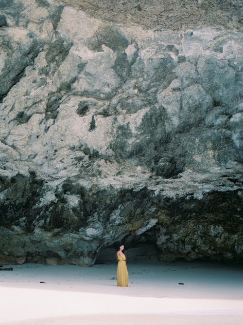 Woman in Yellow Dress Standing in front of Cave 