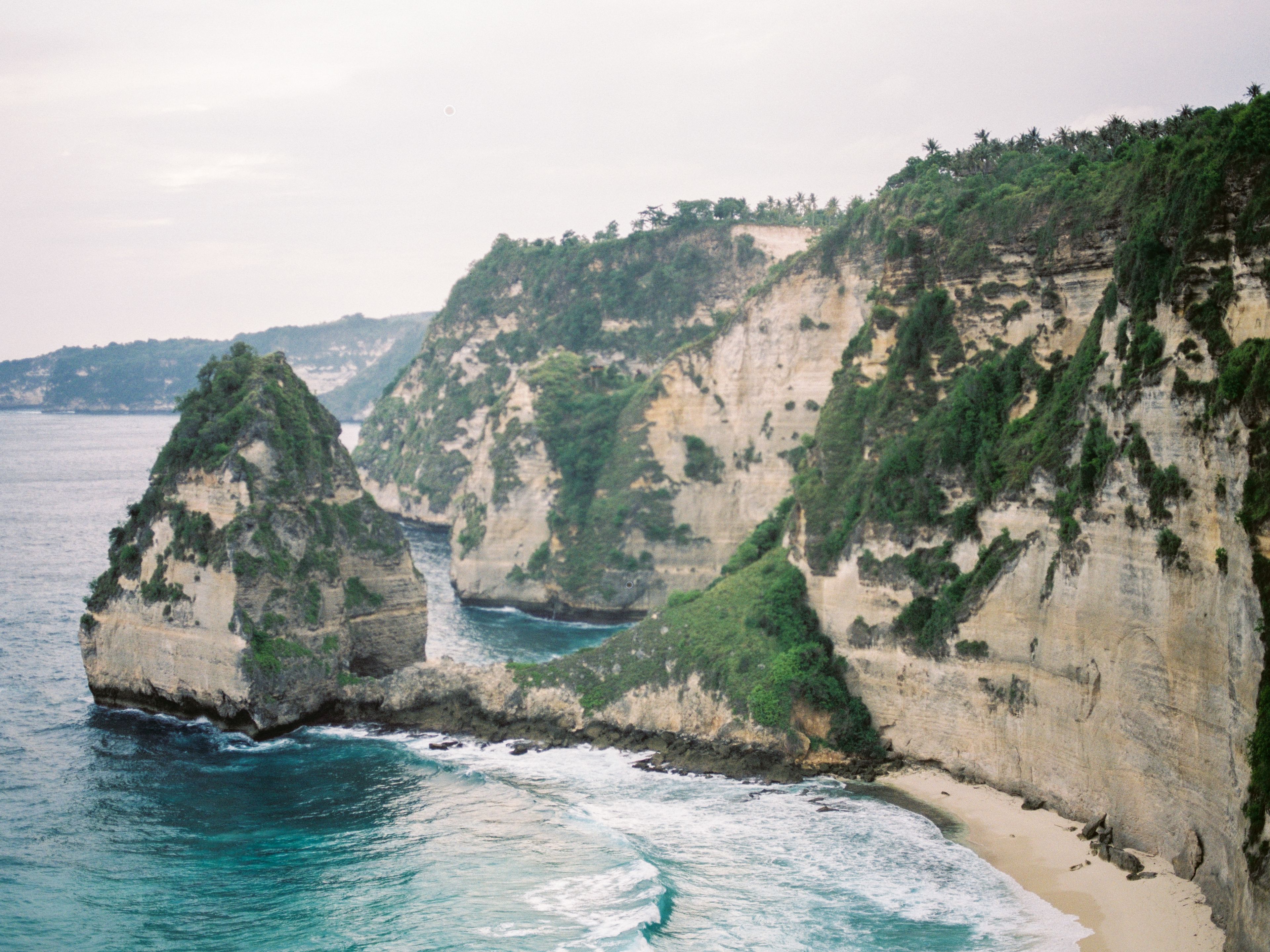 Scenic coastal cliffs with lush greenery, located in Bali, Indonesia, offering a breathtaking natural landscape.