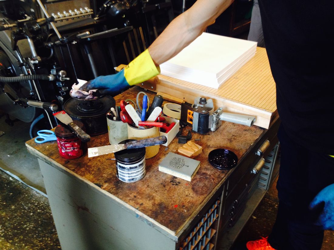 Printshop workspace with tools and inks, showcasing a worker's hand in — Photo by Sibi Mathew on Pexels