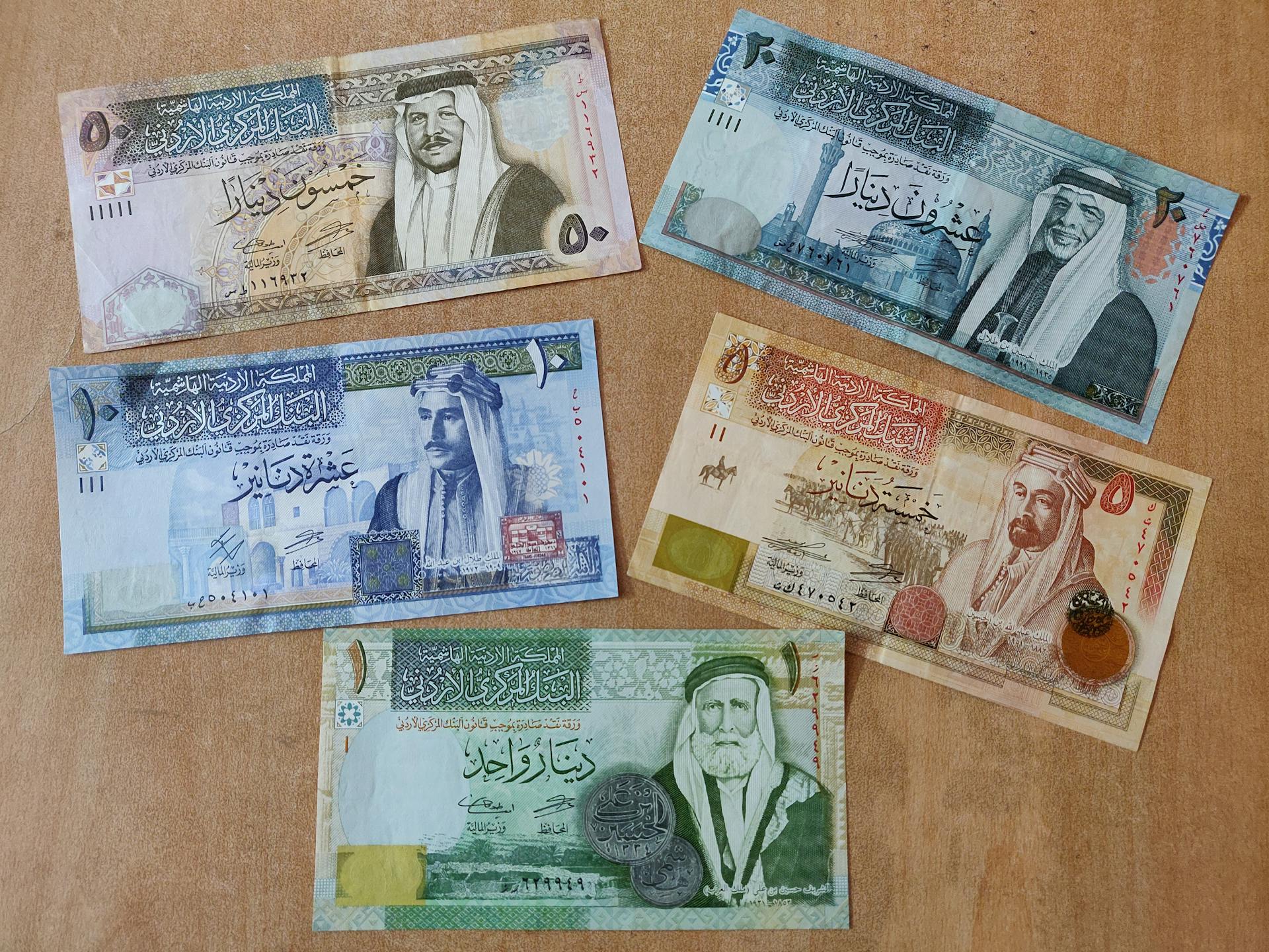 Collection of Jordanian dinar banknotes arranged on a wooden surface, showcasing currency design.