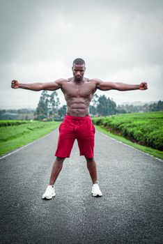 Shirtless man posing confidently on a road in Limuru, embracing fitness and strength.