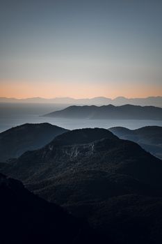 Calm mountain range with layered peaks under a warm twilight sky.