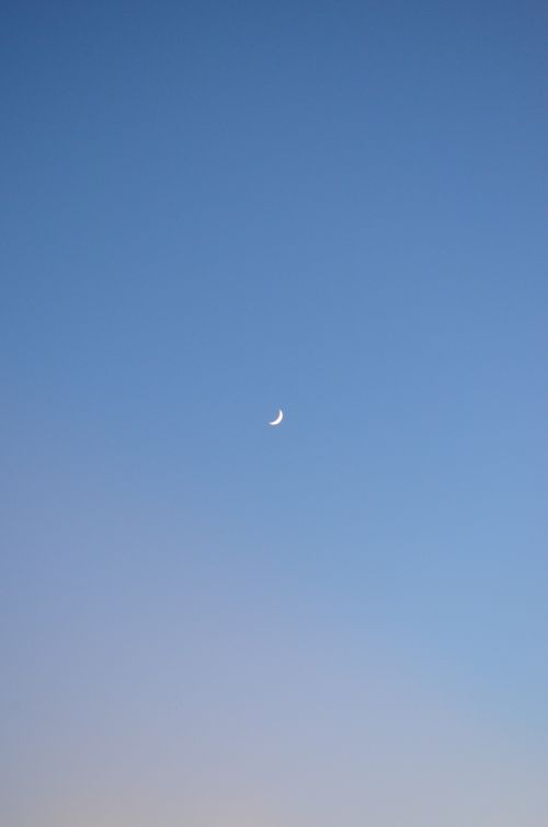 Free Minimalist photo of a crescent moon against a clear blue sky, perfect for backgrounds. Stock Photo