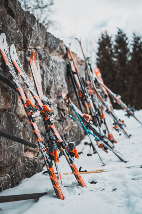 Free Colorful skis leaning against a snowy stone wall, capturing the essence of a lively ski resort in winter. Stock Photo