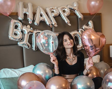 Smiling woman holding balloons during a vibrant birthday celebration indoors.