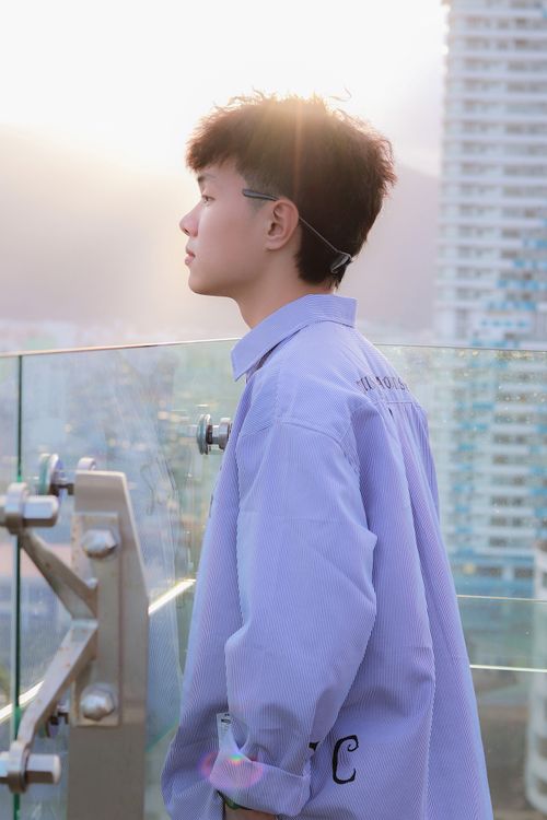 Free Side profile of a young man on a rooftop with city skyline background, enjoying sunset. Stock Photo