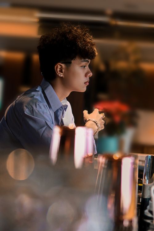 Free Contemplative young man sitting indoors, ambient lighting enhances a peaceful moment. Stock Photo