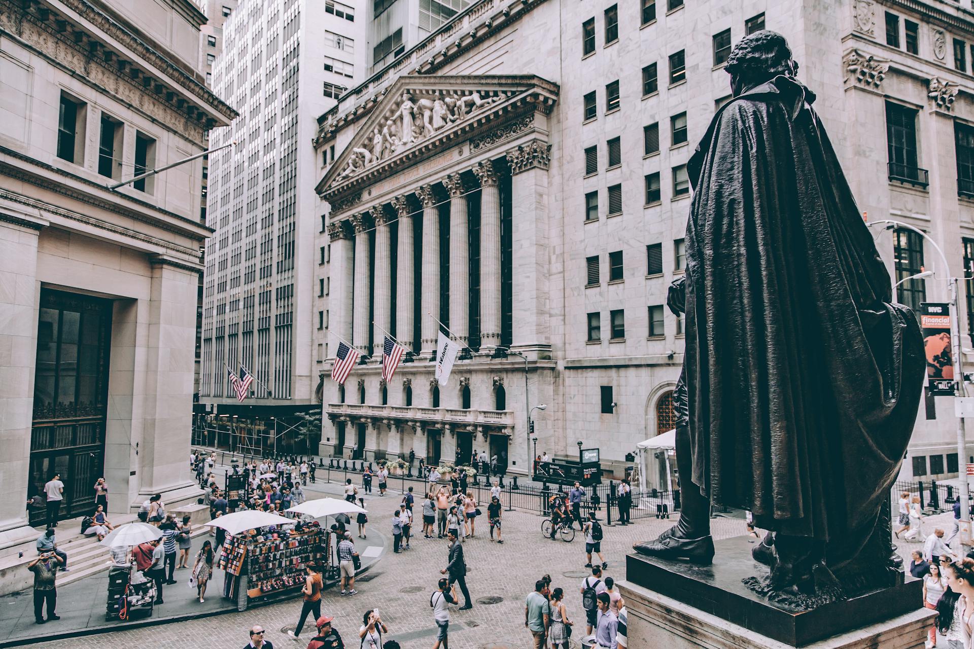 Bustling Wall Street view featuring George Washington statue and New York Stock Exchange.