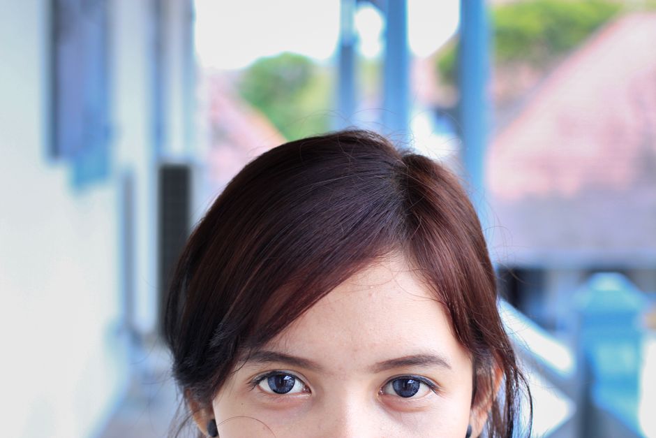 Close-up portrait of a young woman with expressive eyes in an outdoor setting.