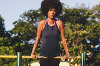 在阳光明媚的日子里，一位女子在户外酒吧锻炼，展示着她的健身成果和力量