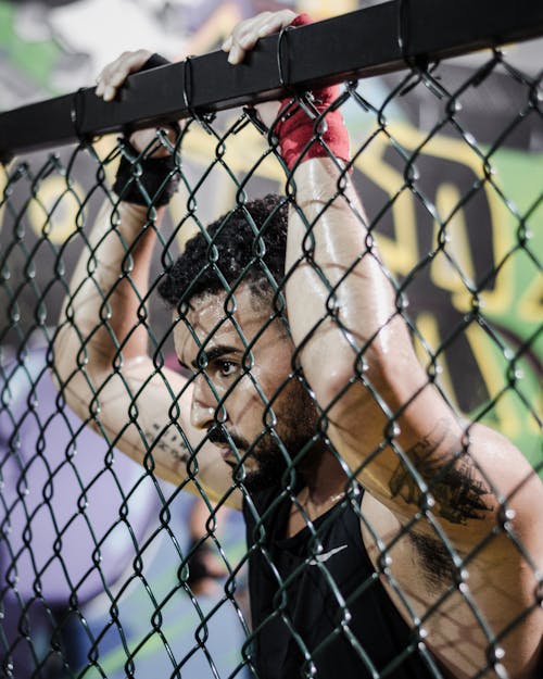 Free Man Wearing Black Tank Top While Holding Fence Stock Photo