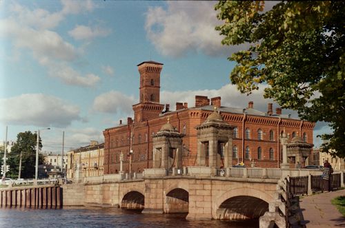 Free Classic architecture with a red brick castle-like building and stone bridge in an urban setting. Stock Photo