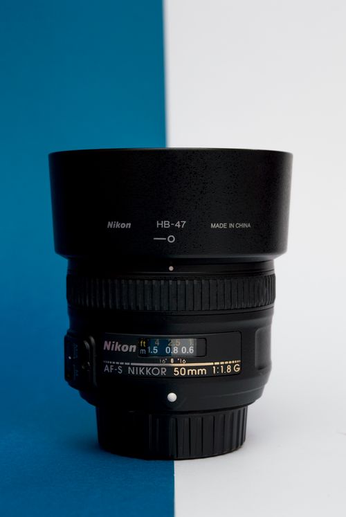 Free A detailed view of a Nikon camera lens against a blue and white background, showcasing its features. Stock Photo