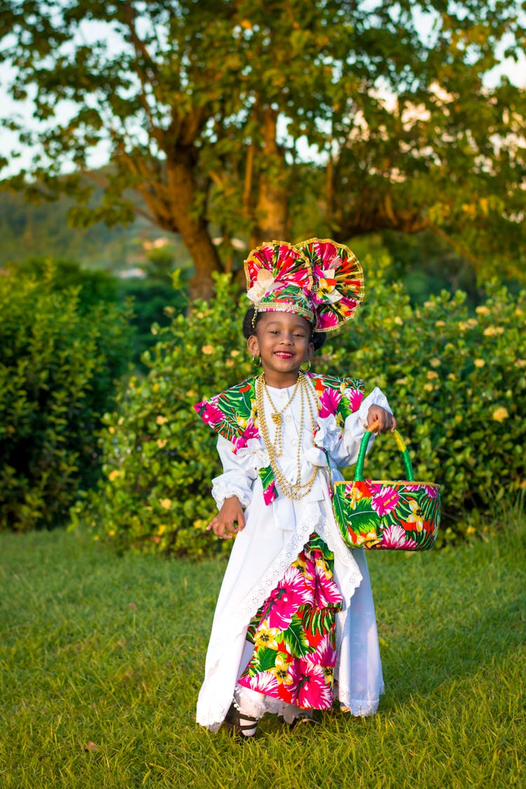 A Young Girl In Traditional Clothes Standing On The Grass While Holding A Basket