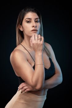 Stylish studio portrait of a young woman in fashionable attire posing confidently.