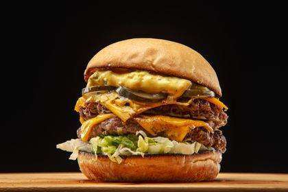 A stacked burger with pickles and lettuce. Photo by Gonzalo Acuña on Pexels.