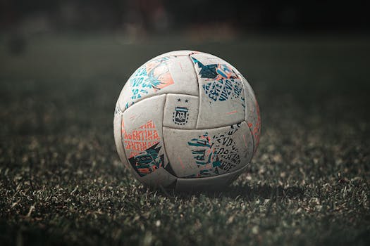 A detailed view of a soccer ball resting on a grassy field, ideal for sports themes.