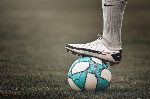 Free A close-up of a soccer shoe resting on a ball on a grassy field; perfect for sports themes. Stock Photo